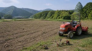 雑草を低く管理した休耕畑と畑の端に停めたトラクター